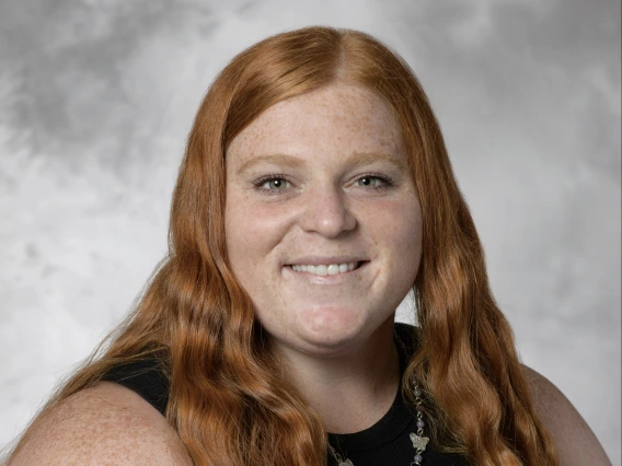 Headshot of Mikayla Deigan: woman with long, wavy red hair wearing a black tank top