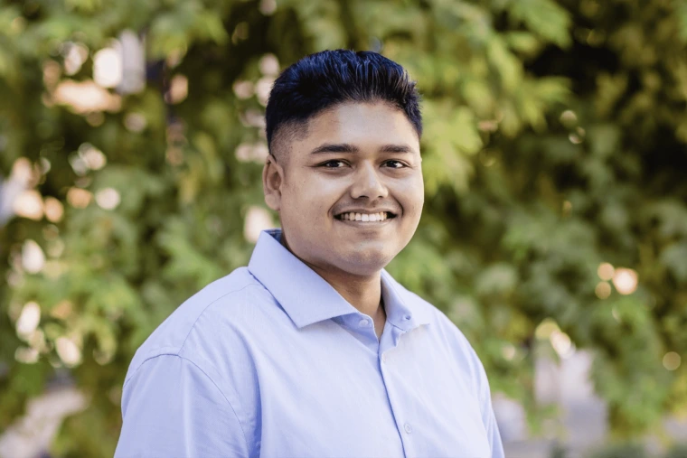 Imran Hossain Mithu - a man with short black hair wearing a blue polo and smiling at the camera. Greenery in the background
