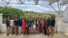 Photo of Carson Scholars 2023-2024 cohort. 13 graduate students standing in a line at Biosphere 2 with the Sonoran Desert in the background.